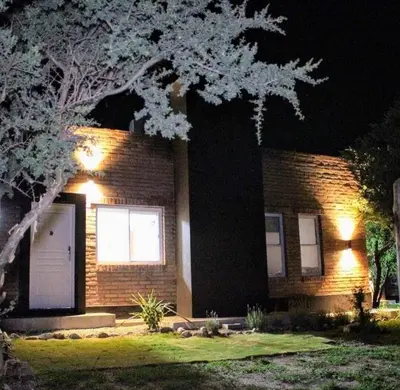 a brick house with a tree in front of it at night at Cabañas Amaneciendo in Merlo