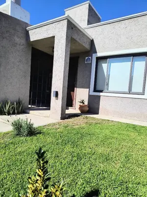 a house with a grass yard in front of it at Casa a 5 minutos de Villa Carlos Paz in Villa San Nicolás