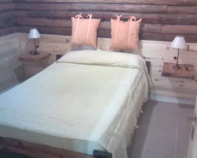 a bedroom with a large bed with two lamps at Cabañas Mc Charlie in Santa Rosa de Calamuchita