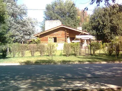 a log house on the side of a road at Cabañas Mc Charlie in Santa Rosa de Calamuchita