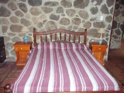 a bed in a room with two nightstands and two lamps at Cabañas Mc Charlie in Santa Rosa de Calamuchita