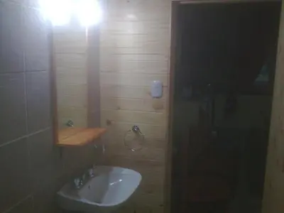 a bathroom with a sink and a light on the wall at Cabañas Mc Charlie in Santa Rosa de Calamuchita