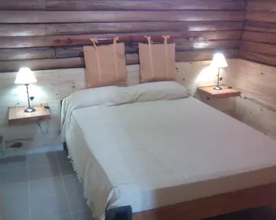 a bedroom with a large bed with two lamps at Cabañas Mc Charlie in Santa Rosa de Calamuchita