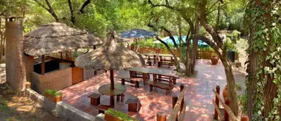 an outdoor patio with tables and umbrellas and trees at Graz Hauser Cabañas in Villa General Belgrano