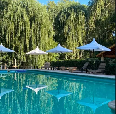 a swimming pool with umbrellas and chairs next to it at Graz Hauser Cabañas in Villa General Belgrano