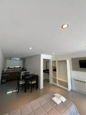 a bedroom with a bed and a table and a kitchen at Graz Hauser Cabañas in Villa General Belgrano