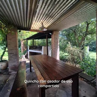 a wooden table under a roof on a patio at Aparts Duendes del Arroyo in Villa General Belgrano