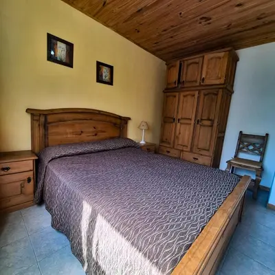 a bedroom with a large bed and wooden cabinets at Aparts Duendes del Arroyo in Villa General Belgrano
