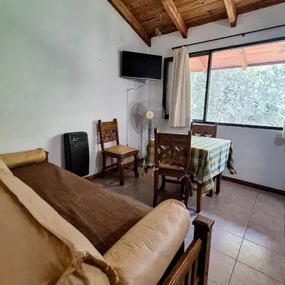 a living room with a bed and a table and chairs at Aparts Duendes del Arroyo in Villa General Belgrano