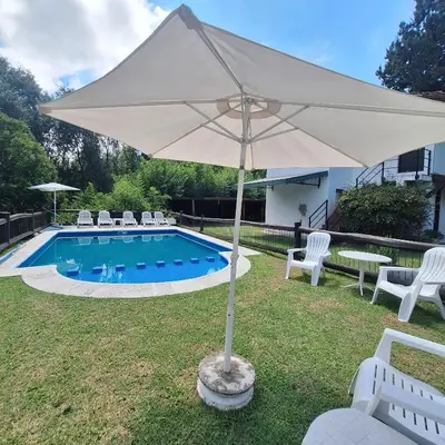 a large white umbrella sitting next to a pool at Aparts Duendes del Arroyo in Villa General Belgrano