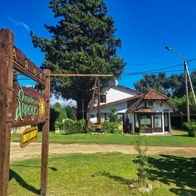 a sign in front of a building with a house at Aparts Duendes del Arroyo in Villa General Belgrano
