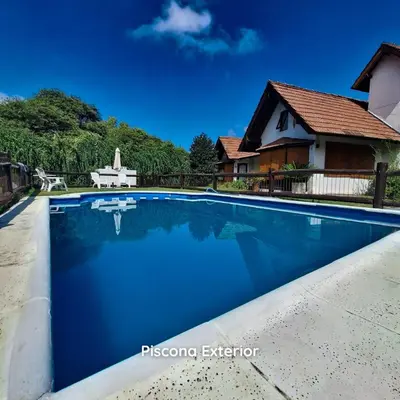 a swimming pool in front of a house at Aparts Duendes del Arroyo in Villa General Belgrano