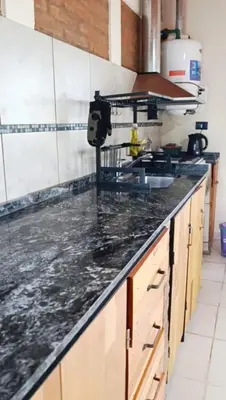 a kitchen with a black counter top with a sink at Casa moderna y nueva, vista a las sierras con cercanía al rio in Los Reartes