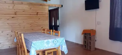 a dining room with a table and chairs and a television at Cabaña cp in Villa General Belgrano