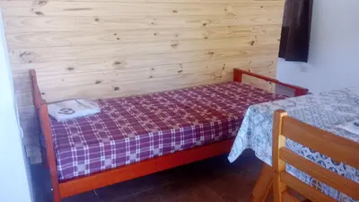 a small bed in a room with a wooden wall at Cabaña cp in Villa General Belgrano