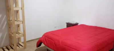 a bedroom with a red bed and a ladder at Cabaña cp in Villa General Belgrano