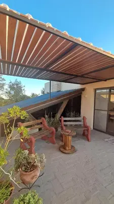 awning over a patio with benches and potted plants at Terrazas al Golf in Alta Gracia