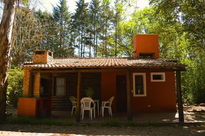 a small cabin with a table and chairs on the porch at Cabañas Altos Del Parque in Villa Ciudad Parque