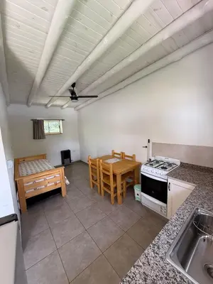 a kitchen and dining room with a table and a stove at Cabañas Al atardecer in Mina Clavero
