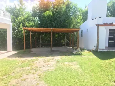 a pavilion in a yard next to a white building at Cabañas Al atardecer in Mina Clavero