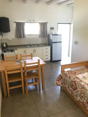 a kitchen with a table and chairs and a dining room at Cabañas Al atardecer in Mina Clavero