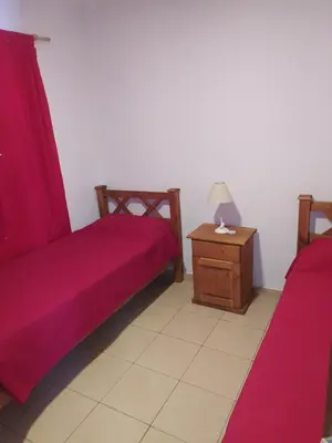 a room with two beds and a table with a lamp at Luma Departamento, con Pileta in Villa Dolores