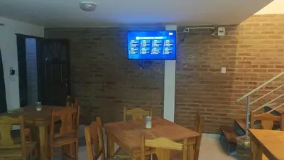 a dining room with two tables and a tv on a brick wall at Luma Departamento, con Pileta in Villa Dolores