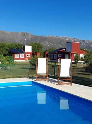 a pool with two empty chairs next to a house at Cabañas Tinkuy II in Cortaderas
