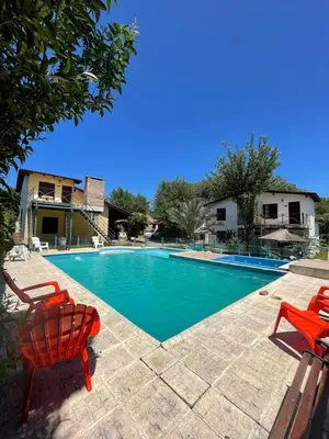 a swimming pool with two red chairs next to it at Cabañas Calimocho in Santa Rosa de Calamuchita