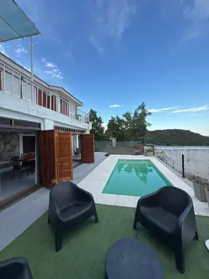 a house with a swimming pool and two chairs at Playas Doradas in Villa Anizacate