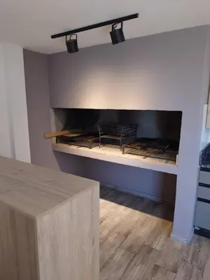 a fireplace in a room with a wooden table at Village Tower III sobre Av San Martín, Cochera in Villa Carlos Paz
