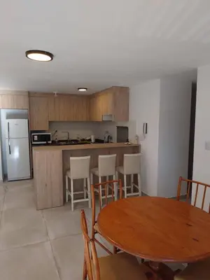 a kitchen and dining room with a table and a refrigerator at Village Tower III sobre Av San Martín, Cochera in Villa Carlos Paz