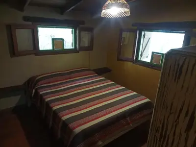 a small bedroom with a bed and two windows at Tierra linda in Las Chacras (La Paz)