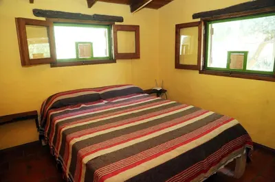 a bedroom with a bed with a colorful striped blanket at Tierra linda in Las Chacras (La Paz)