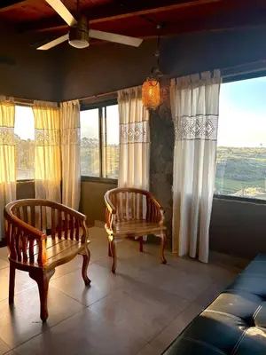two chairs and a couch in a room with windows at Cabaña Casa Flor Bru in Villa Yacanto