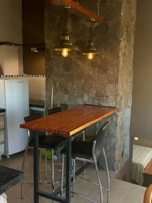 a dining room table with chairs and a stone wall at Cabaña Casa Flor Bru in Villa Yacanto