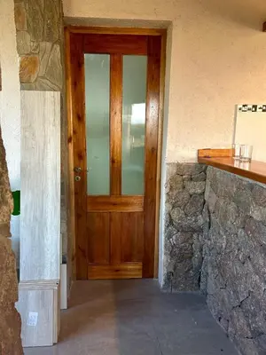 a wooden door in a room with a stone wall at Cabaña Casa Flor Bru in Villa Yacanto