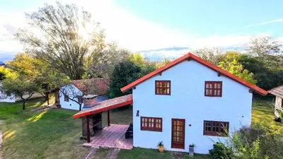 a white house with a red roof on a field at Lomas de Belgrano Oficial cabaña 1 in Villa General Belgrano