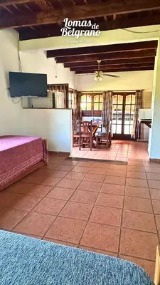 a room with a bed and a table with a piano at Lomas de Belgrano Oficial cabaña 1 in Villa General Belgrano