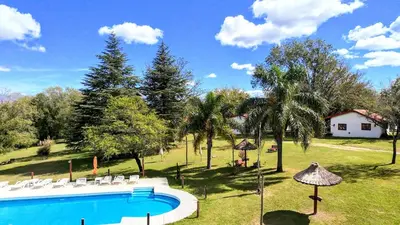 a swimming pool with chairs and a house in the background at Lomas de Belgrano Oficial cabaña 1 in Villa General Belgrano