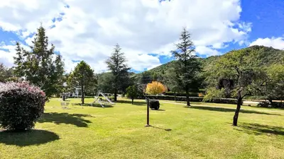 a park with trees and a swing set in the grass at Lomas de Belgrano Oficial cabaña 1 in Villa General Belgrano