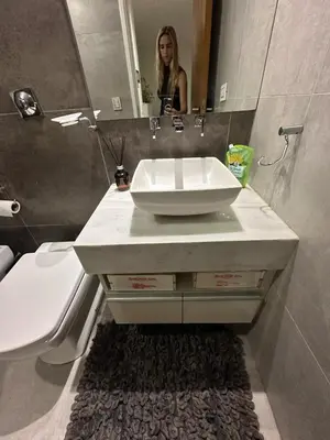 a woman standing in front of a sink in a bathroom at CERRO DE LAS ROSAS Departamento amoblado con pileta climatizada in Cordoba