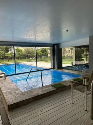 a large swimming pool in a building with windows at CERRO DE LAS ROSAS Departamento amoblado con pileta climatizada in Cordoba