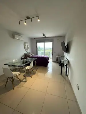 a living room with a table and a bed at CERRO DE LAS ROSAS Departamento amoblado con pileta climatizada in Cordoba
