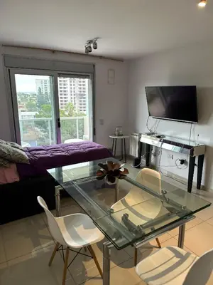 a living room with a glass table and chairs at CERRO DE LAS ROSAS Departamento amoblado con pileta climatizada in Cordoba