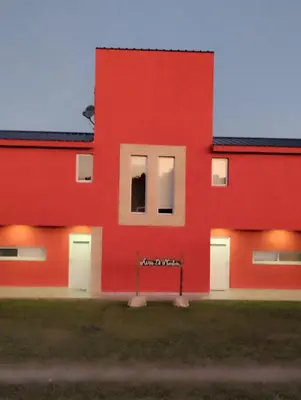 a red building with white doors and windows at Cabañas Potrero de Garay in La Estancia