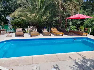 a swimming pool with chairs and a red umbrella at EnlodelLuly in Villa Carlos Paz
