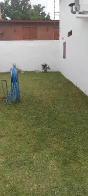 a yard with a blue chair sitting in the grass at Duplex la casita de papá in Mina Clavero