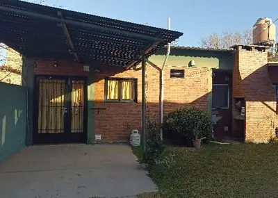 a brick house with a door and a porch at Duplex la casita de papá in Mina Clavero