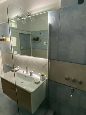 a bathroom with a sink and a shower with a mirror at Departamento Centro Córdoba con Cochera Privada in Cordoba